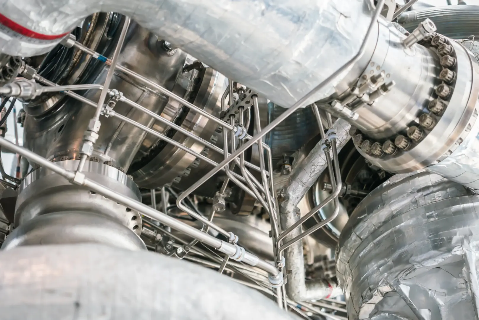 Close-up of stainless steel industrial machinery with numerous tubes, bolts, and fittings.